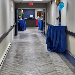 A decorated hallway set up for an event, featuring blue tables and festive balloons.