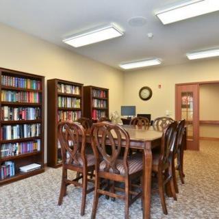 A cozy library with wooden furniture and filled bookshelves.