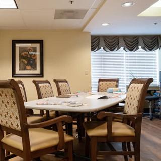 A well-appointed dining or meeting room with a large table and comfortable chairs, featuring decorative elements and natural light from the windows.