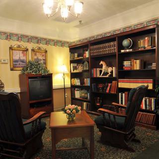 A cozy living room with bookshelves, armchairs, and a television.