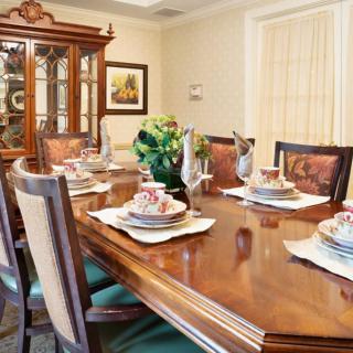 An elegant dining room with a formally set table, featuring a china cabinet and decorative elements.