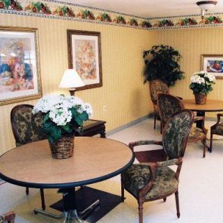 A cozy interior room with tables and chairs, decorative plants, and framed artwork on the walls.