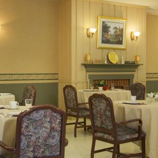 A cozy dining room with elegantly set tables, a fireplace, and decorative elements.