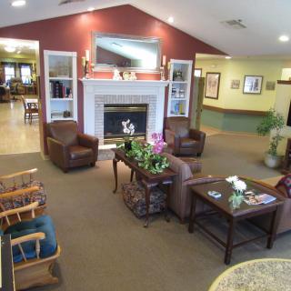 A cozy lobby with comfortable seating around a fireplace, adorned with decorative elements.