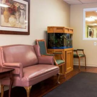 A comfortable waiting room featuring a pink sofa, an aquarium, and wall art.