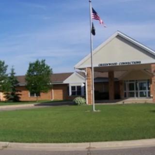 A school building with an American flag in front and a grassy lawn.