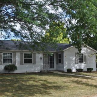 A cozy suburban house surrounded by trees and a well-maintained yard.