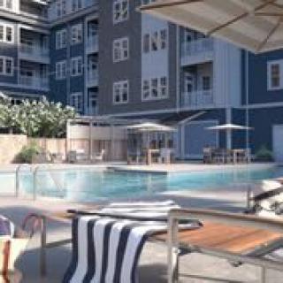 A modern apartment complex featuring an outdoor pool area with loungers and umbrellas.
