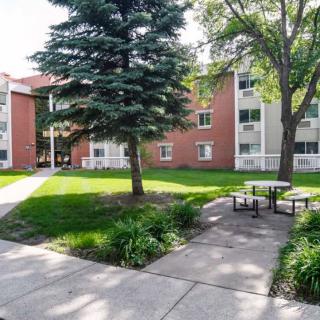 A peaceful residential apartment complex with lush greenery and outdoor seating areas.