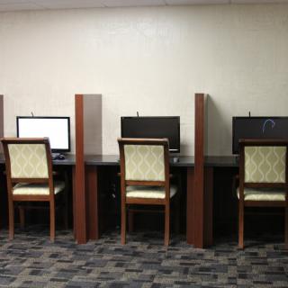 A row of workstations in a computer lab or office space with chairs and computers.
