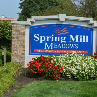 A landscaped entrance sign for Spring Mill Meadows surrounded by colorful flowers.