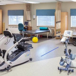 A physical therapy room equipped with various exercise machines and treatment tables.