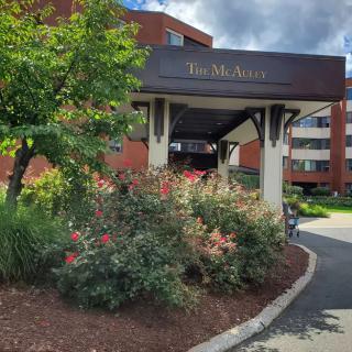 Entrance to a building with landscaped surroundings and a covered walkway.