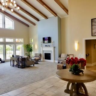 A spacious living room with a high vaulted ceiling, modern furniture, and large windows providing ample natural light.