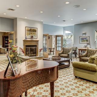 A cozy living room with a grand piano, fireplace, and comfortable seating.