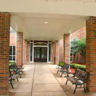 Brick building entrance with benches lining the pathway.