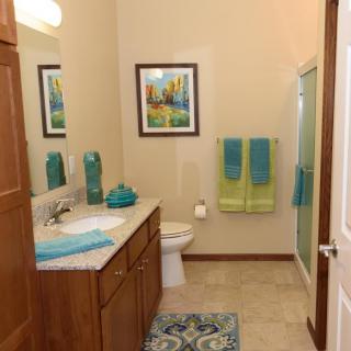 A neatly organized bathroom with colorful towels and wall art.