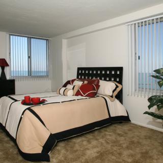 A modern bedroom with a neatly made bed and large windows.
