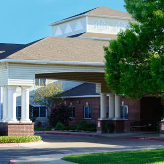 A front view of a building with a covered entrance and landscaped surroundings.