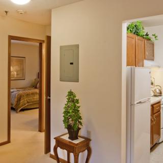 A view of a home interior showing a hallway leading to a bedroom and kitchen.