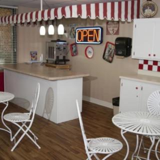 A retro-style diner interior with a countertop, tables, and chairs.