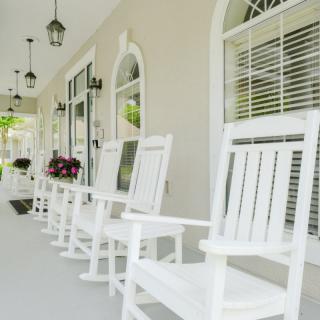 A cozy porch featuring white rocking chairs and hanging lights.