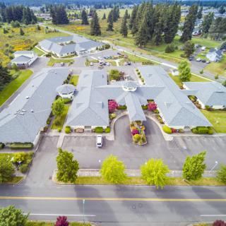 Aerial view of a building complex surrounded by greenery and a road.