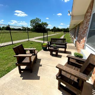 A cozy outdoor seating area with wooden chairs and a beautiful green landscape.