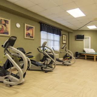 A well-equipped gym area designed for exercise and rehabilitation, featuring various cardio machines.