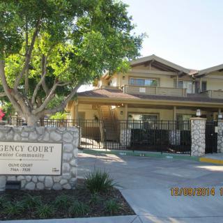 Entrance to a residential apartment complex with a prominent sign and gated entrance.