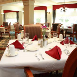 An elegantly set dining table in a restaurant with red napkins and neatly arranged tableware.