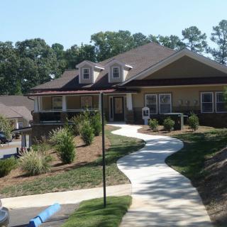 A residential house with landscaped gardens and a winding pathway leading to the entrance.