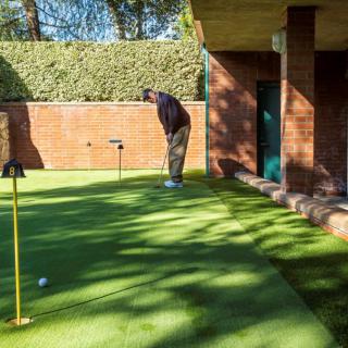 A man practicing his putting skills in an outdoor garden setting.