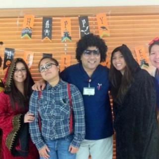A group of people in costumes celebrating Halloween with festive decorations in the background.