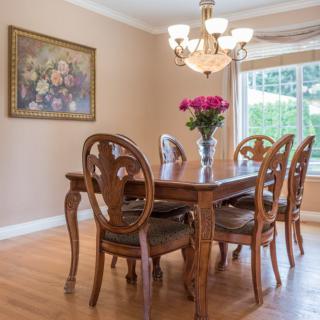 A beautifully decorated dining room with wooden furniture, a floral centerpiece, and a chandelier.