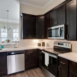 A modern kitchen with dark cabinets and stainless steel appliances.