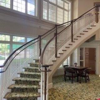 A modern interior featuring a curved staircase with elegant railing and large windows.