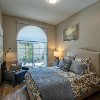 A cozy bedroom with a large window, comfortable chair, and elegant decor.