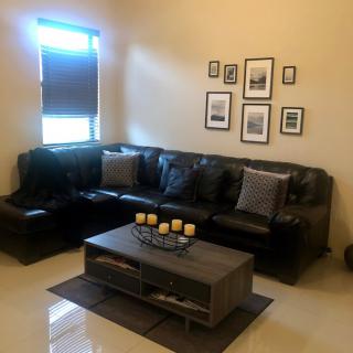 A cozy living room with a black leather sofa, decorated with cushions and wall art, accompanied by a stylish coffee table.