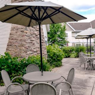 A serene outdoor seating area featuring tables with umbrellas surrounded by lush greenery.
