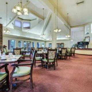 A spacious dining room with elegant chandeliers, large windows, and neatly arranged tables and chairs.