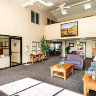 A spacious and well-lit waiting area with comfortable seating, plants, and artwork on the walls.