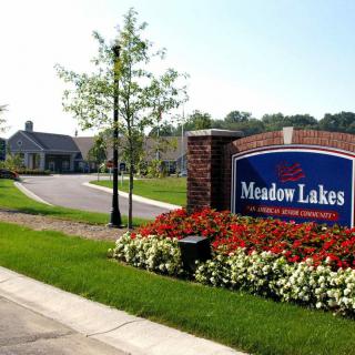 Entrance to Meadow Lakes residential community with a landscaped sign and surrounding greenery.