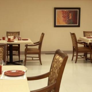 An empty dining area with neatly arranged tables and chairs, featuring artwork on the wall.