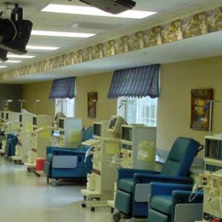 A dialysis center with treatment chairs and medical equipment lined up in a well-lit room.