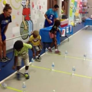 Children participating in an indoor activity involving a race with bottles.