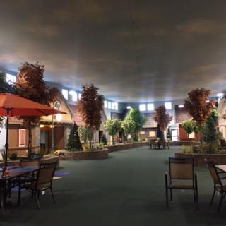 A cozy indoor shopping area featuring decorative trees and seating arrangements under a softly lit ceiling.