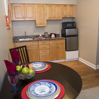 A cozy kitchen featuring wooden cabinets and a small dining area with a table set for two, complete with fresh fruits.