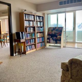 Cozy living room with bookshelves filled with books, a large window, and a comfortable chair.