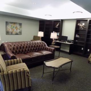 A cozy living room featuring a leather sofa, striped armchair, coffee table, and bookshelves.